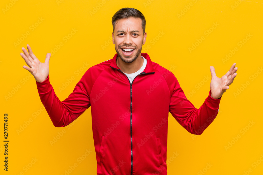 Young filipino fitness man receiving a pleasant surprise, excited and raising hands. Young filipino fitness man receiving a pleasant surprise, excited and raising hands.
