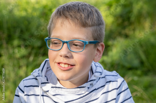 portrait of a boy in blue glasses on green background