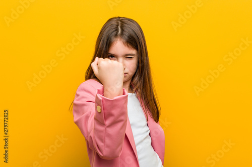 Little caucasian cute girl showing fist to camera, aggressive facial expression.