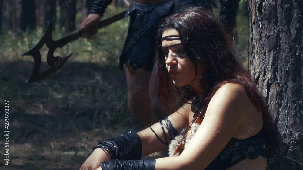 Ancient woman in leather clothes fights a barbarian man, in the forest Ancient woman in leather clothes fights a barbarian man, in the forest