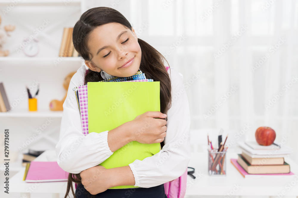 Ethnic schoolgirl closing eyes hugging notebooks Ethnic schoolgirl closing eyes hugging notebooks