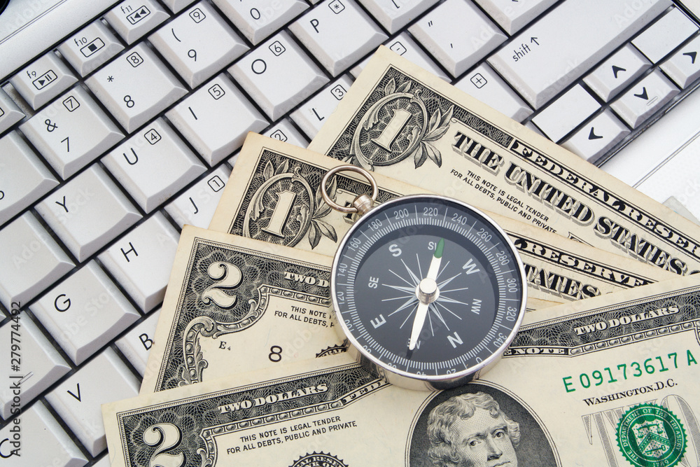 Online investitions, compass and money on conouter keyboard Online investitions, compass and money on conouter keyboard