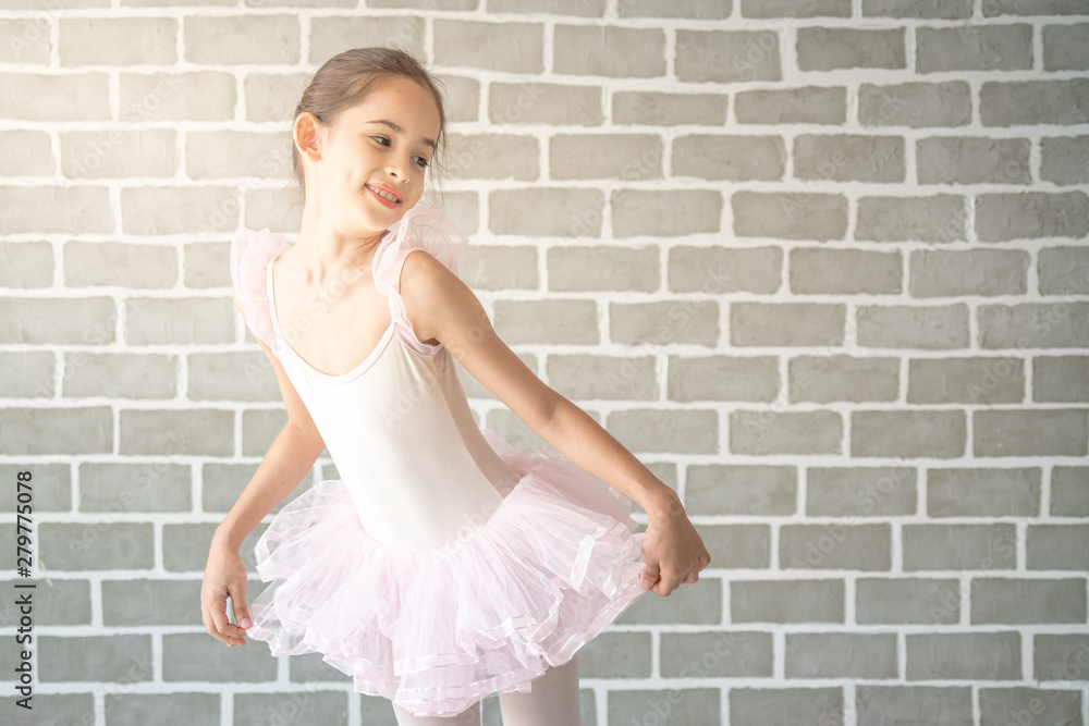 Cute little young girl ballerina dancer in pink leotard and tutu are  dancing in studio room