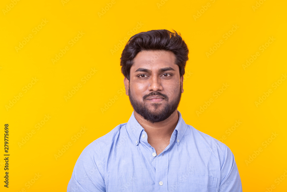Indian handsome man wearing blue shirt on yellow background Indian handsome man wearing blue shirt on yellow background