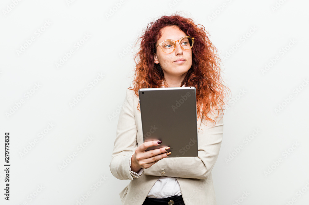Young caucasian business redhead woman holding a tablet smiling confident with crossed arms. Young caucasian business redhead woman holding a tablet smiling confident with crossed arms.