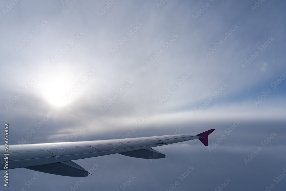 Up in the air, view of aircraft wing silhouette with dark blue sky horizon and cloud background in sun rise time, viewed from airplane window Up in the air, view of aircraft wing silhouette with dark blue sky horizon and cloud background in sun rise time, viewed from airplane window
