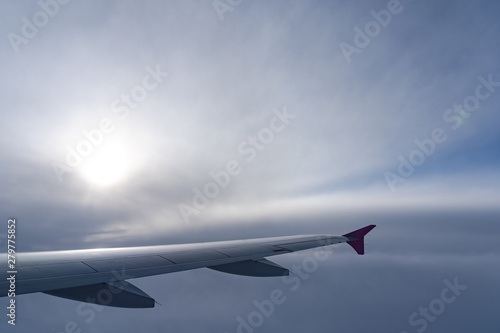 Up in the air  view of aircraft wing silhouette with dark blue sky horizon and cloud background in sun rise time  viewed from airplane window