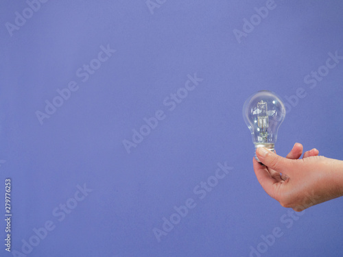 Hand with light bulb    on purple background and copy space - concept