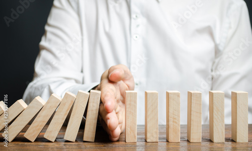 Tableau sur toile Businessman stops domino falling