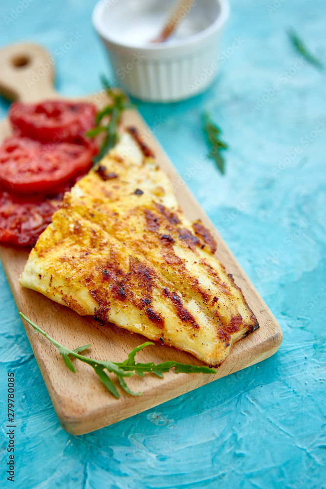 Grilled pike fillet with tomatoes on wooden board Grilled pike fillet with tomatoes on wooden board