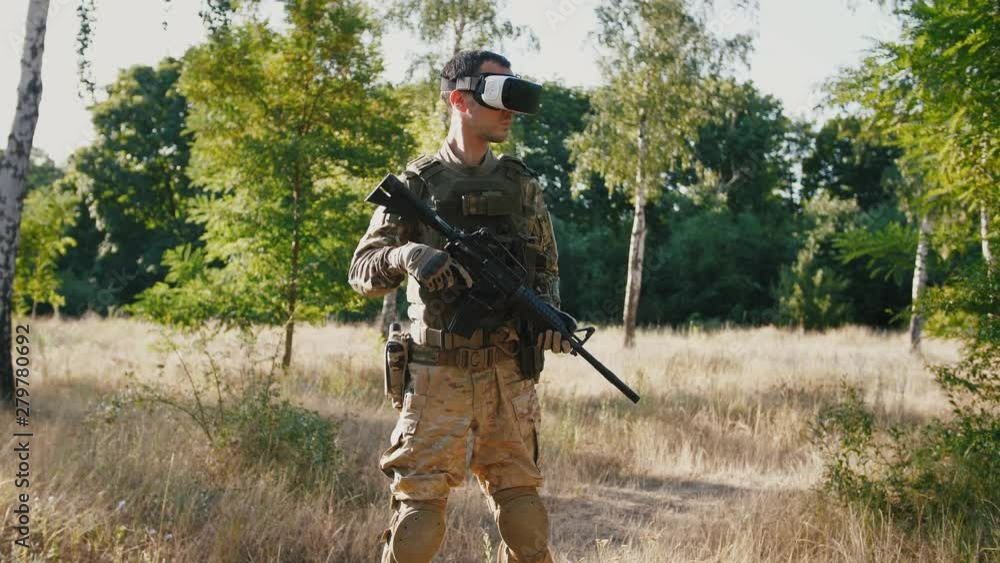 Soldier with rifle wearing virtual reality glasses outdoors Soldier with rifle wearing virtual reality glasses outdoors