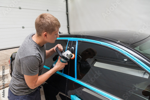 The polisher polishes the body of the vehicle with special wax to protect the car from minor scratches and damage, using a polishing machine to cover black door after washing. Auto service industry