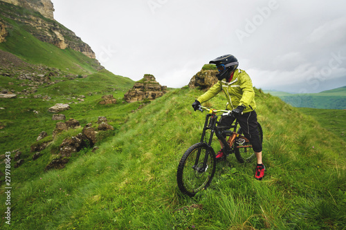 Side view of a man on a mountain bike standing on a rocky terrain and looking at a rock. The concept of a mountain bike and mtb downhill