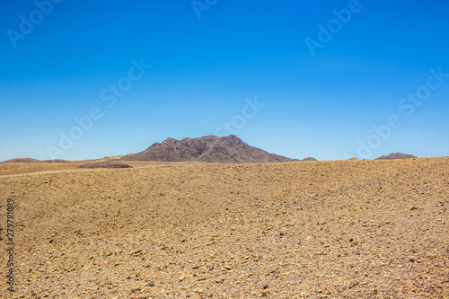 minimalism landscape of desert sand stone valley foreground and lonely mountain ridge background 