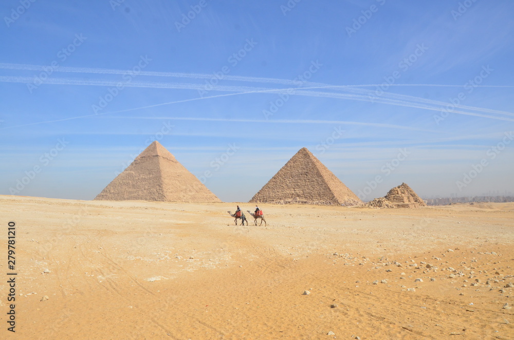 Egypt. Cairo - Giza. General view of pyramids from the Giza Plateau. Tourist riding camel crossing the desert.