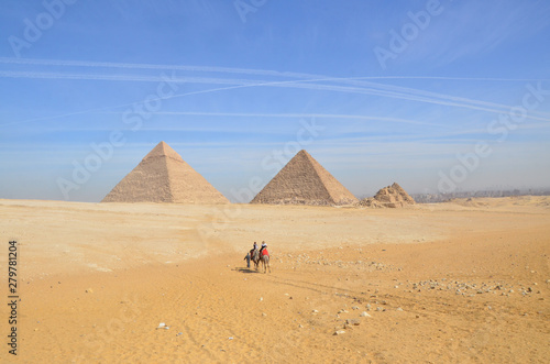 Egypt. Cairo - Giza. General view of pyramids from the Giza Plateau. Tourist riding camel crossing the desert.