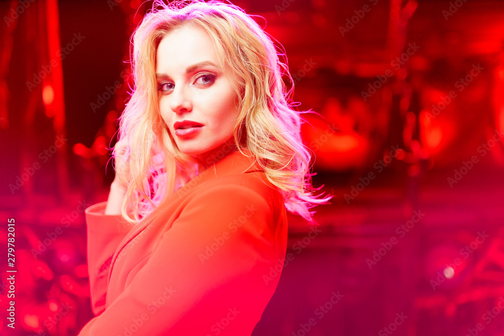 Photo of blonde girl in red jacket standing on red background Photo of blonde girl in red jacket standing on red background