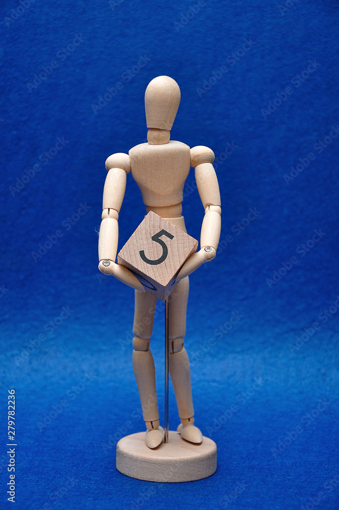 A wooden mannequin with a wooden block with the number five A wooden mannequin with a wooden block with the number five