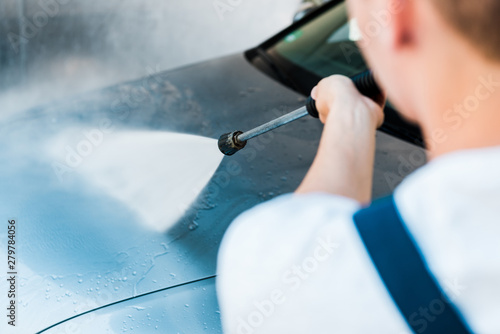 selective focus of man washing grey auto outside