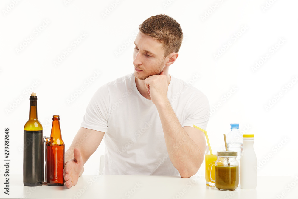 Muscular guy looking at different drinks in front of him. Muscular guy looking at different drinks in front of him.