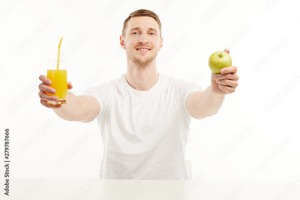 Muscular guy holding a glass of orange juice with a straw and a green apple. Muscular guy holding a glass of orange juice with a straw and a green apple.