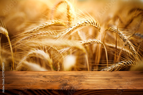 Golden ears of wheat with wooden table photo