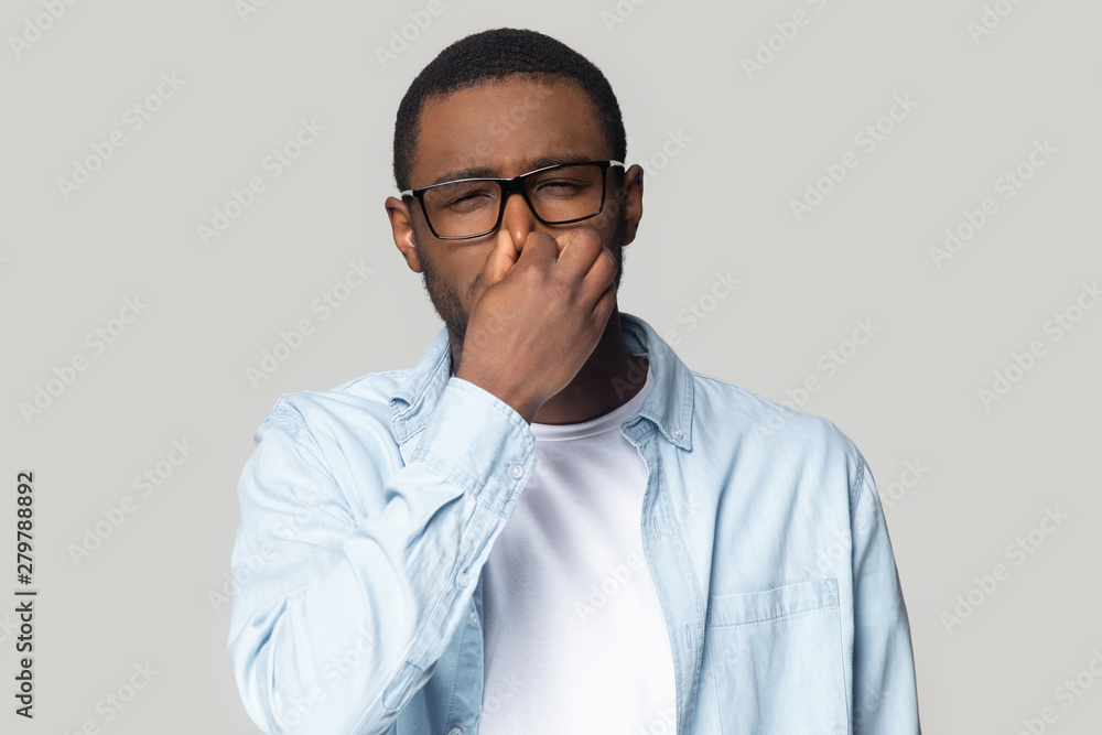 Unhappy african American man cover nose avoid bad smell Unhappy african American man cover nose avoid bad smell