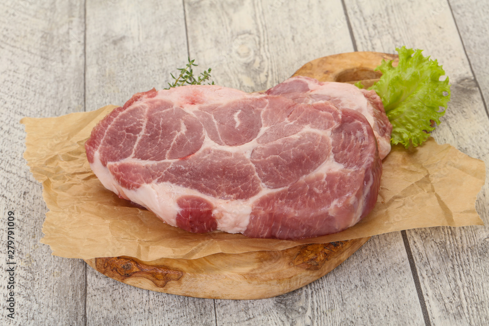 Raw pork steak over wooden board