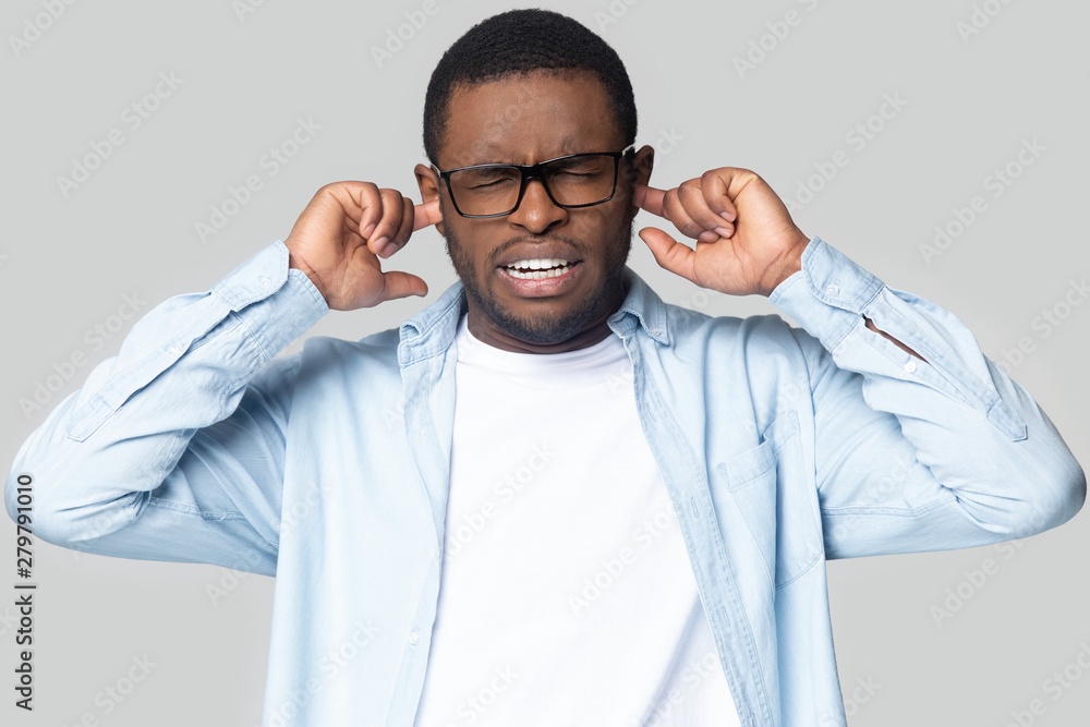 Annoyed black man plug ears avoiding disturbing sound Stock Photo