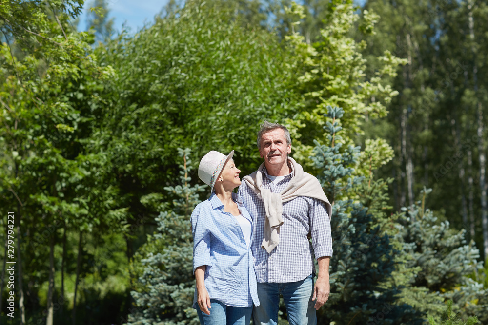 Portrait of happy senior couple posing in garden lit by bright sunlight, copy space Portrait of happy senior couple posing in garden lit by bright sunlight, copy space