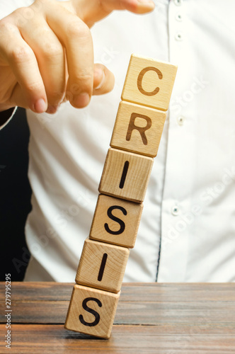 Businessman removes wooden blocks with the word Crisis. The exit from the crisis and financial stability. Focus on resolving the midlife crisis. The rise of the economy and business development.