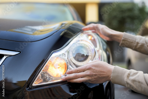 Hand holding headlight of darkÂ car photo