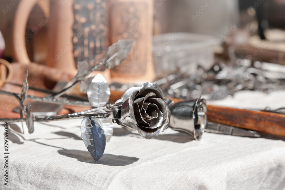 Handmade forged metal rose on white background on craft festival 
