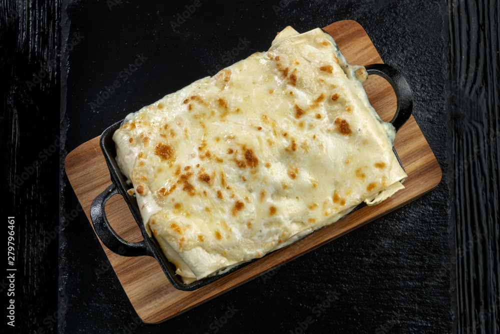 Piece of tasty hot lasagna. Traditional italian lasagna on a cast iron pan.