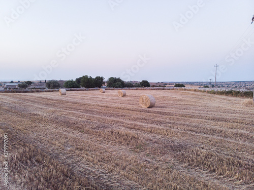 Aerial view of a field full of wheat bales at sunrise