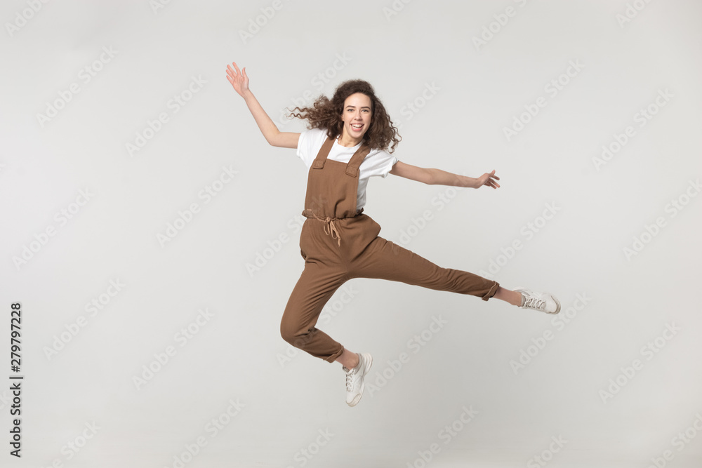 Happy active woman jumping in studio isolated on grey background