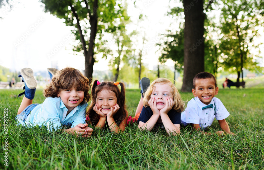 four friends of preschool kids playing lying on the grass in the Park on a summer day four friends of preschool kids playing lying on the grass in the Park on a summer day