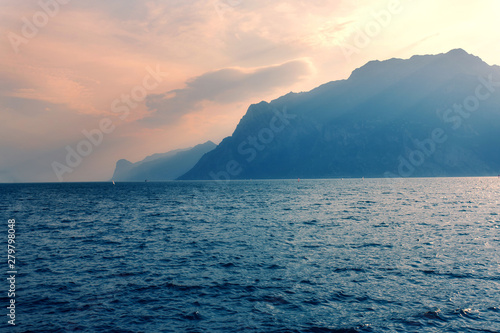 Amazing oprange sunset with mountain and sea views  sun rays and the blue water of lake Garda Italy