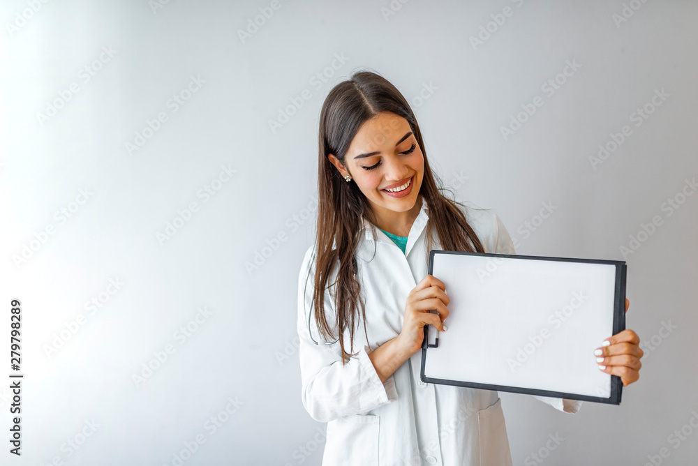 Happy doctor holding empty blank in hands. Female doctor showing a clipboard with blank paper. Close-up of a female doctor with lab coat and holding blank clipboard Happy doctor holding empty blank in hands. Female doctor showing a clipboard with blank paper. Close-up of a female doctor with lab coat and holding blank clipboard