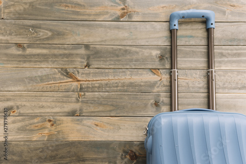Blue travel suitcase against wooden background