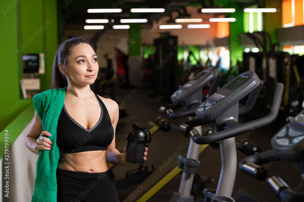 Smiling fit girl holding towel and taking rest in gym. Smiling fit girl holding towel and taking rest in gym.