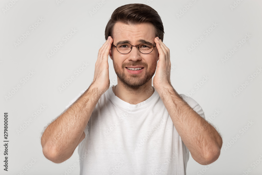 Fototapeta premium Stressed man touching temples suffering from headache studio shot