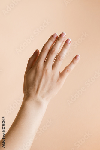 Manicured woman's hand on pale orange background