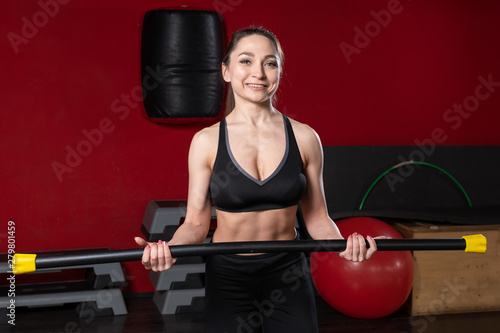 Fitness young blond woman holds gymnastic body bar stick in her hand in the gym