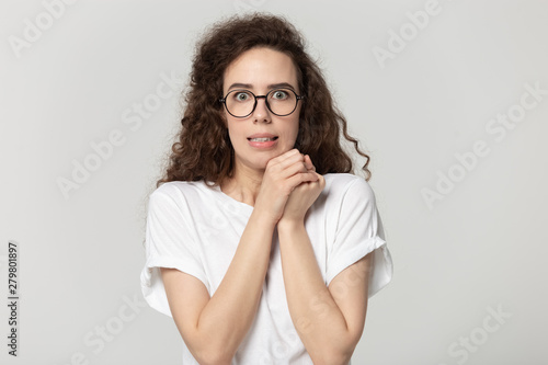 Scared young woman looking at camera posing on grey background