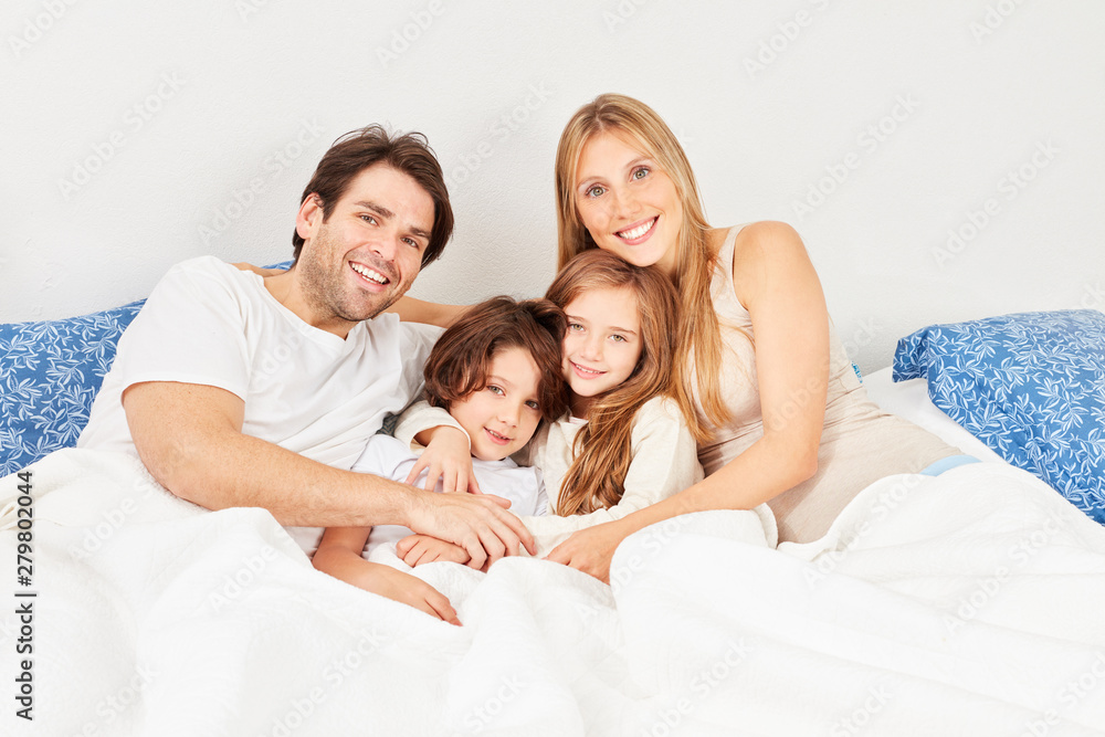 Glückliche Familie mit zwei Kindern im Bett