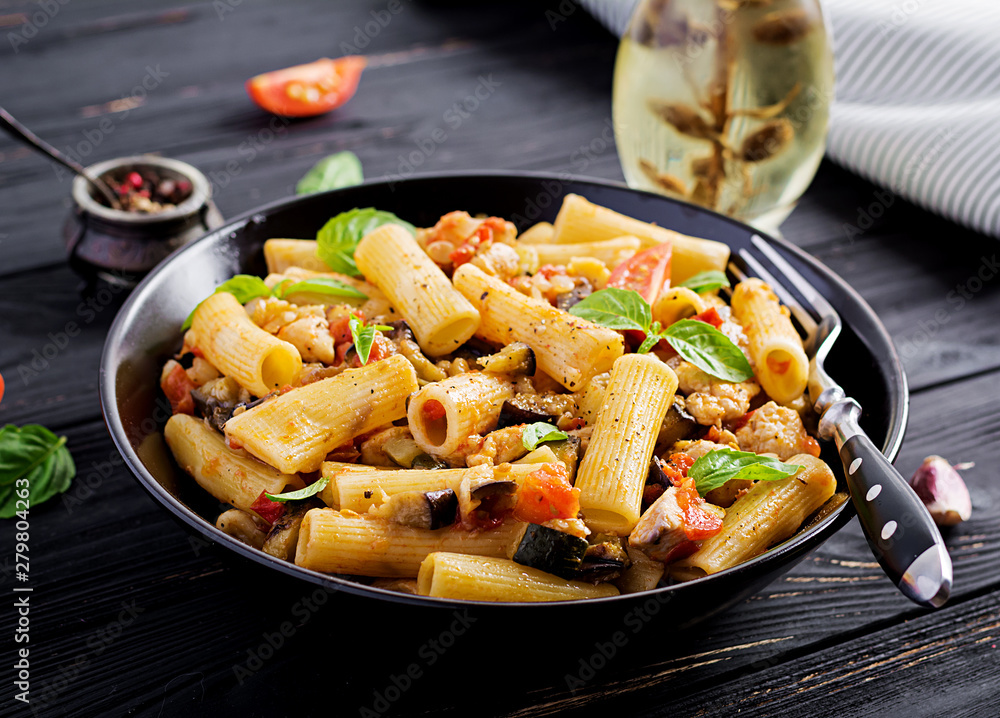 Rigatoni pasta with chicken meat, eggplant in tomato sauce in bowl. Italian cuisine.