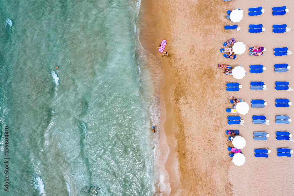 Aerial view of beautiful sandy beach with umbrellas and sunbeds and chairs. Relax on the beach. Sandy seashore place for rest.