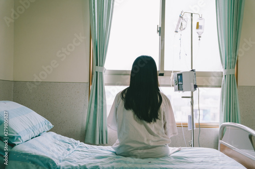 female patient with dropper looks out the window