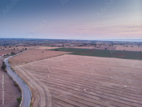 Aerial view of a field full of wheat bales at sunrise